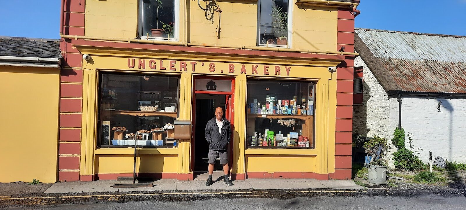 The full yellow-and-red façade of Unglert's Bakery with the owner in the doorway