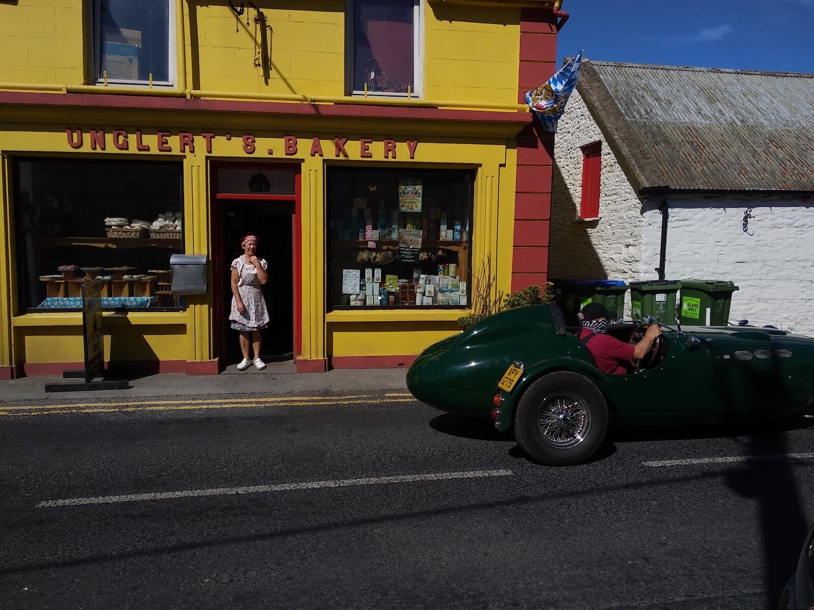 Unglert's Bakery's bright yellow shopfront with the hand-painted red sign, on a sunny day in Ennistymon